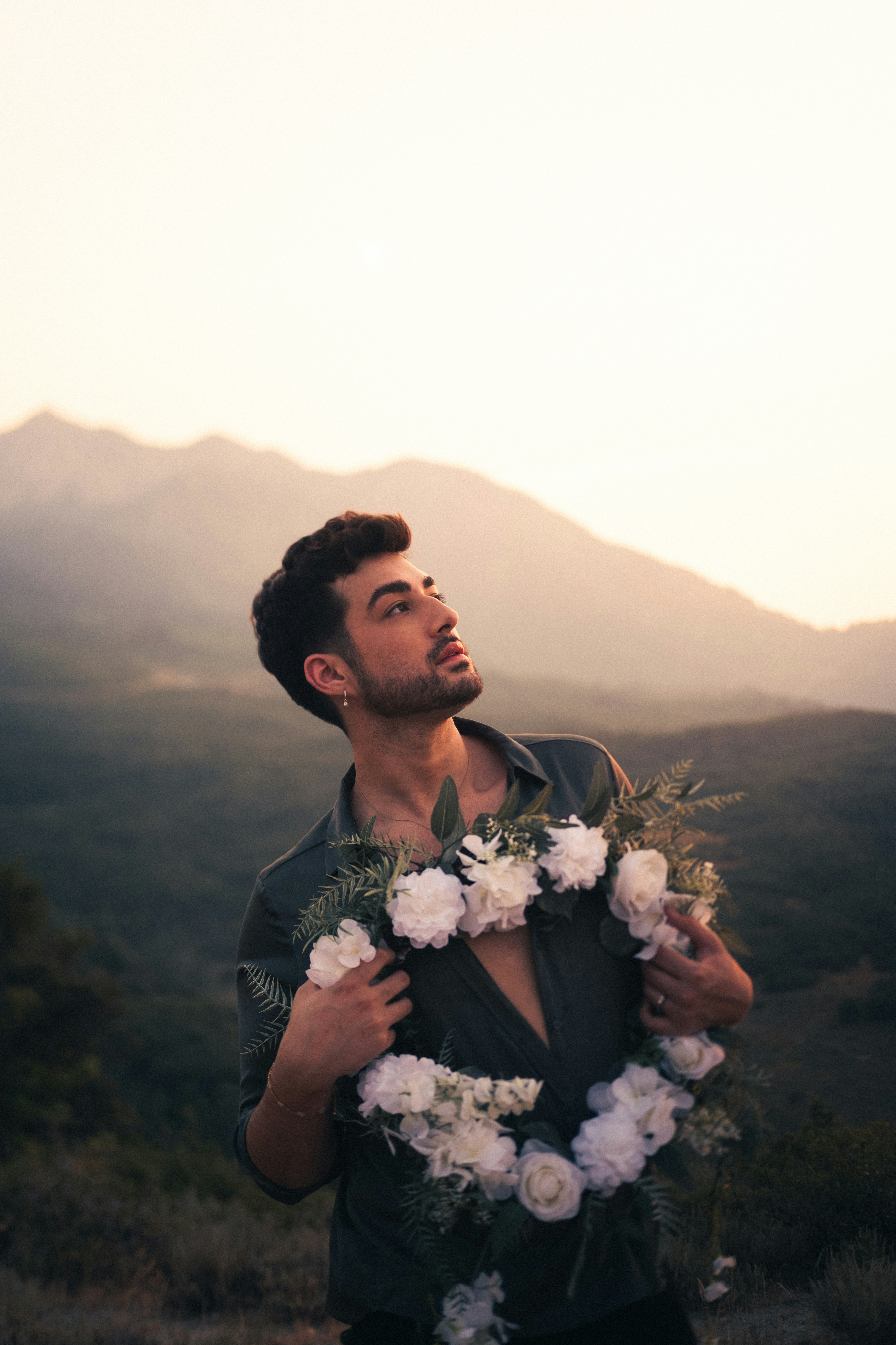 man in black suit holding white flower bouquet